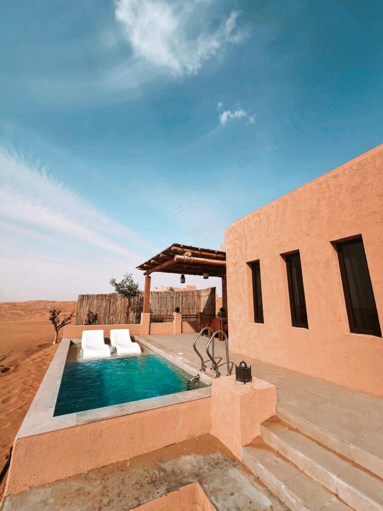 Elegant desert bungalow with a pool, deckchairs, and stunning sky in UAE.